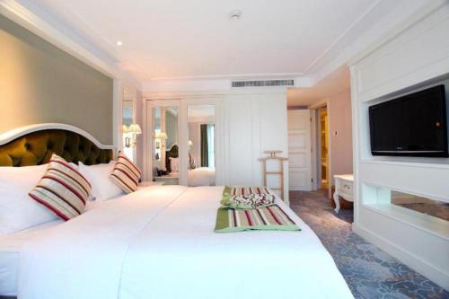 a bedroom with a large white bed with a flat screen tv at Xiamen Jingmin Central Hotel in Xiamen