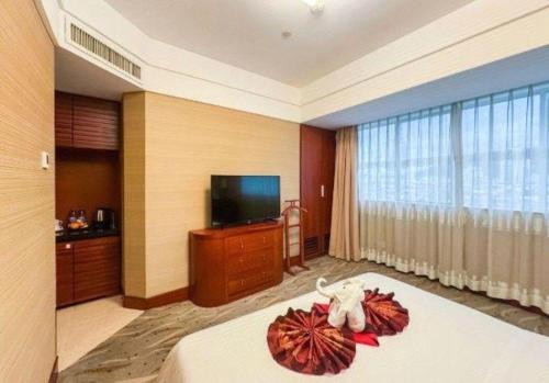 a hotel room with a bed and a flat screen tv at Xiamen Jingmin Central Hotel in Xiamen