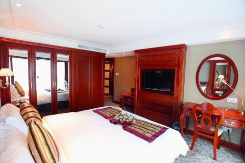 a bedroom with a bed and a desk and a television at Xiamen Jingmin Central Hotel in Xiamen