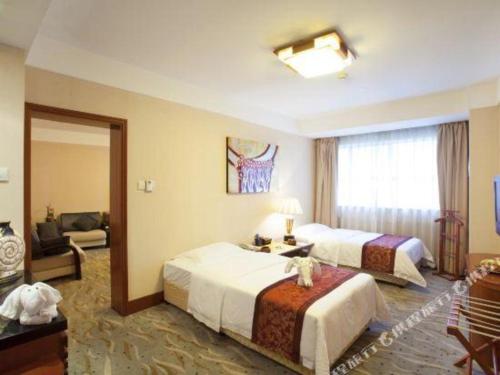a hotel room with two beds and a mirror at Xiamen Jingmin Central Hotel in Xiamen
