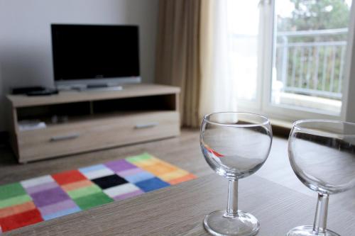 zwei Weingläser auf einem Tisch vor einem Fernseher in der Unterkunft Apartmentcenter Koblenz in Koblenz