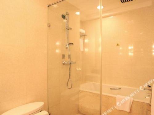 a bathroom with a shower with a toilet and a glass door at Xiamen Jingmin Central Hotel in Xiamen