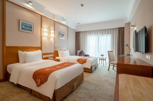 Una habitación de hotel con dos camas y un televisor. en Qingdao Blue Horizon Hotel Huangdao, en Huangdao