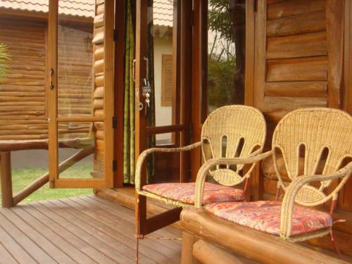 two wicker chairs sitting on the porch of a cabin at Indie House @ Maerim in Chiang Mai