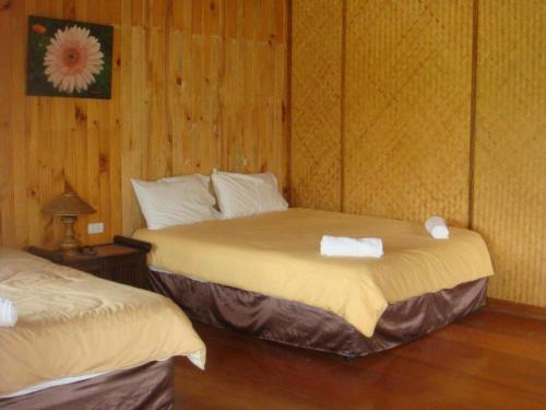 two beds in a room with wooden walls at Indie House @ Maerim in Chiang Mai