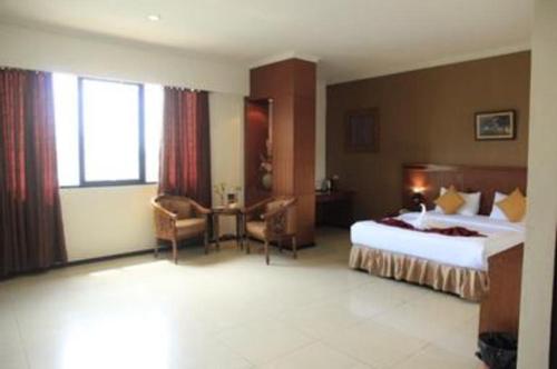 a hotel room with two beds and a desk at Garuda Hotel Pontianak in Pontianak