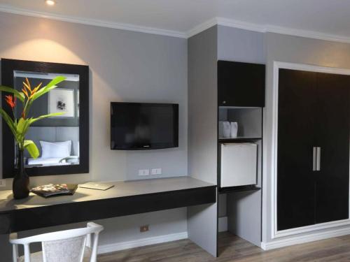 a room with a desk with a tv and a room with a bed at Regent Park Hotel in Phnom Penh