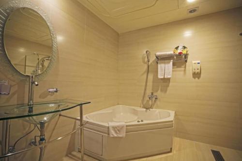 a bathroom with a sink and a mirror and a tub at Metro Tourist Hotel Cheonan in Cheonan