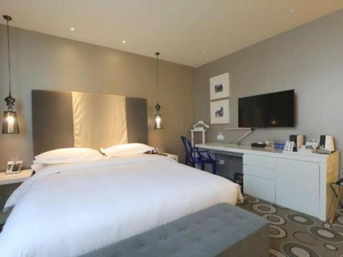 a bedroom with a large white bed and a desk at Jinjiang Metropolo Hotel Classiq Shanghai Off Bund in Shanghai