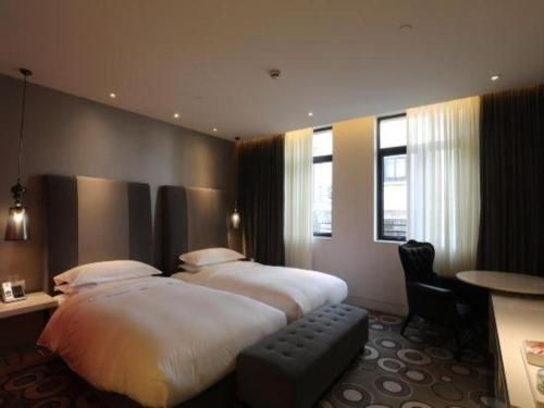 a hotel room with a large bed and a desk at Jinjiang Metropolo Hotel Classiq Shanghai Off Bund in Shanghai