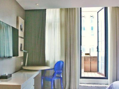 a blue chair in a room with a window at Jinjiang Metropolo Hotel Classiq Shanghai Off Bund in Shanghai