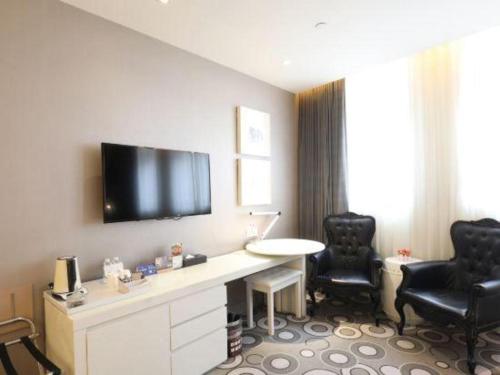 a hotel room with a desk and a tv on the wall at Jinjiang Metropolo Hotel Classiq Shanghai Off Bund in Shanghai