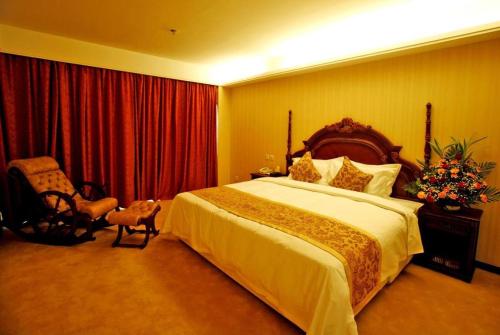 a bedroom with a large bed and a chair at Yanji Yanbian International Hotel in Yanji