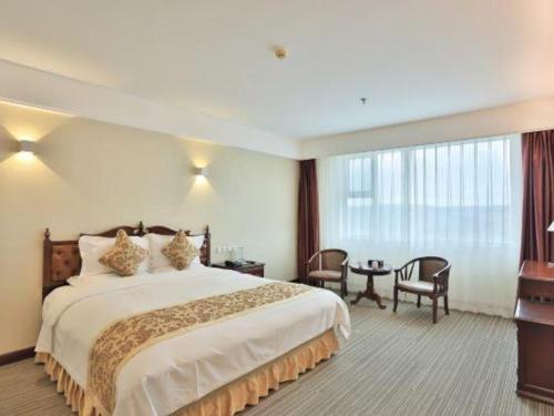 a hotel room with a large bed and a table at Yanji Yanbian International Hotel in Yanji