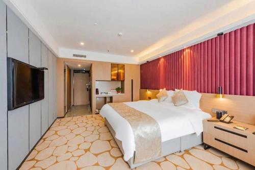 a bedroom with a large bed and a flat screen tv at Yanji Yanbian International Hotel in Yanji