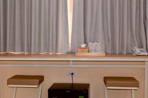 a counter with two stools in front of a window at Bangsaen Villa Hotel in Si Racha