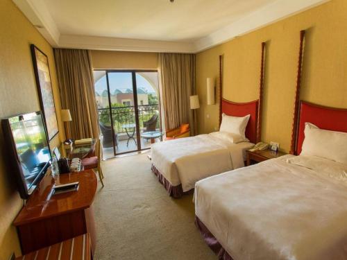 a hotel room with two beds and a television at Ocean Spring Metropark Hotel Zhuhai in Zhuhai