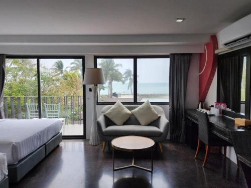 a bedroom with a bed and a couch and a table at Eco Moment Beach Resort in Phetchaburi