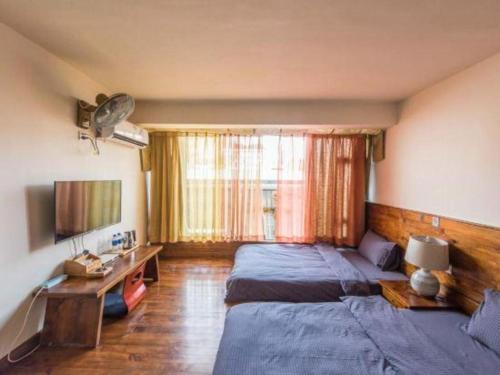 a bedroom with two beds and a desk and a television at Dali Four Seasons Hostel in Dali Ancient Town