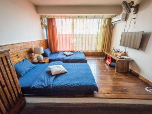 a bedroom with two beds with blue sheets in it at Dali Four Seasons Hostel in Dali Ancient Town