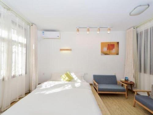 a bedroom with a white bed and a blue chair at Dali Four Seasons Hostel in Dali Ancient Town
