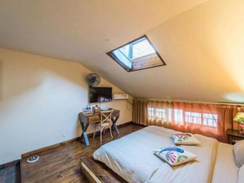 a bedroom with a bed and a window and a desk at Dali Four Seasons Hostel in Dali Ancient Town