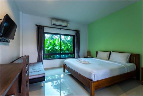 ein Schlafzimmer mit einem Bett und einem Fernseher und einem Fenster in der Unterkunft Tamali Hotel in Ban Yuan Lae