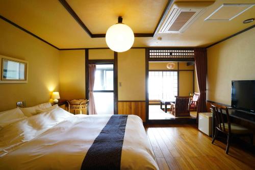 a bedroom with a bed and a television and a table at 桐のかほり咲楽 in Kawazu