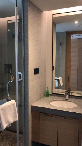 a bathroom with a sink and a shower with a mirror at New Century Kylie Hotel Ningbo in Ningbo