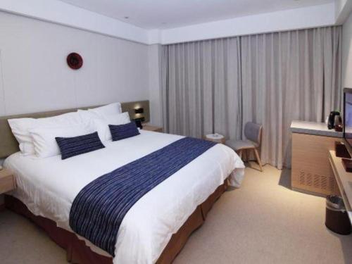 a hotel room with a large bed and a television at New Century Kylie Hotel Ningbo in Ningbo