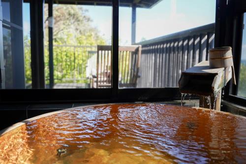 a bath tub with water coming out of it at 桐のかほり咲楽 in Kawazu