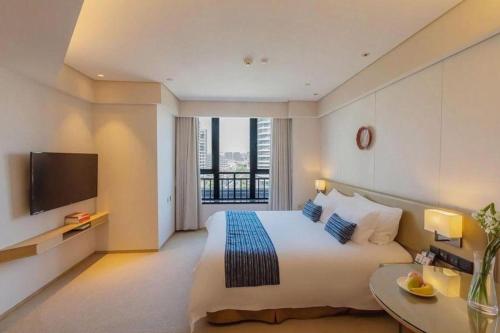 a hotel room with a bed and a television at New Century Kylie Hotel Ningbo in Ningbo