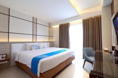 a bedroom with a large bed and a chair at Java Lotus Hotel Jember in Jember