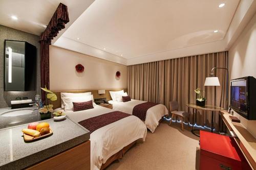 a hotel room with two beds and a flat screen tv at New Century Kylie Hotel Ningbo in Ningbo