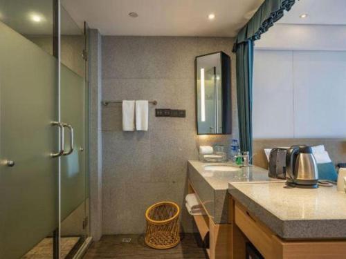 a bathroom with a glass shower and a sink at New Century Kylie Hotel Ningbo in Ningbo