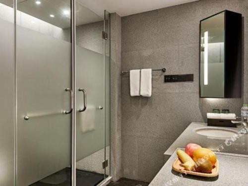 a bathroom with a sink and a glass shower at New Century Kylie Hotel Ningbo in Ningbo