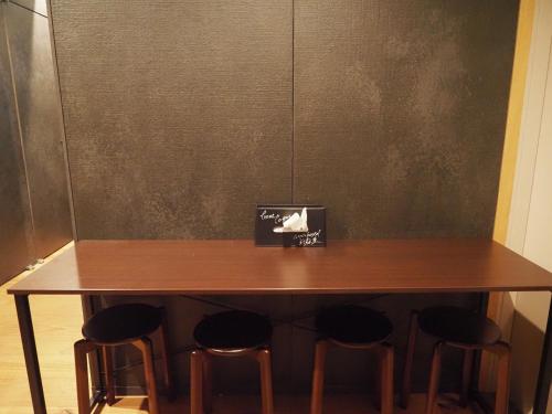 a wooden table with four stools around it at Capsule Hotel Suzumoriya in Tokyo
