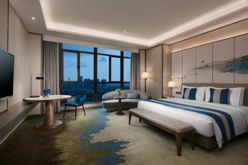 a hotel room with a large bed and a television at Rosedale Hotel Taicang in Taicang