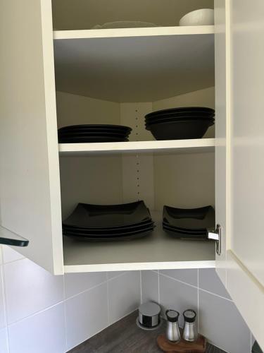 a cupboard filled with black plates and bowls at Maria apartment with Sauna Otta in Otta