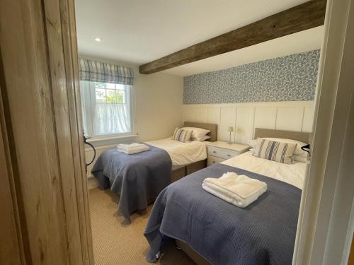 a room with two beds with towels on them at Wisteria Cottage - 2 bed near Bath & many NT sites in Holt