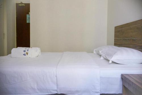 a white bed with white sheets and pillows on it at JH Hotel in Singapore