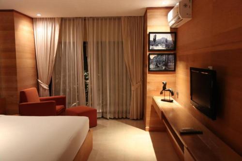 ein Hotelzimmer mit einem Bett und einem Fernseher in der Unterkunft The Bonanza Resort Khaoyai in Khanong Phra