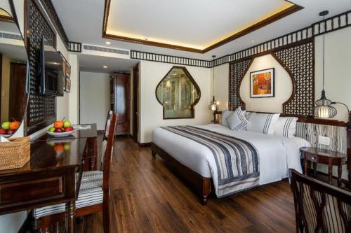 a hotel room with a bed and a desk and a table at Le Pavillon Hoi An Paradise Hotel & Spa in Hoi An