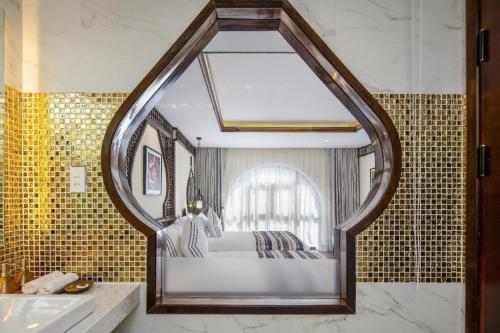 a bedroom with a bed in a bathroom with a mirror at Le Pavillon Hoi An Paradise Hotel & Spa in Hoi An
