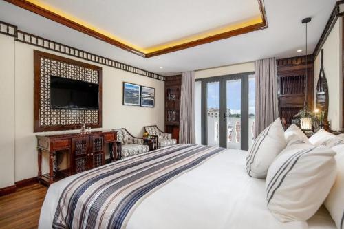 a bedroom with a large bed and a television at Le Pavillon Hoi An Paradise Hotel & Spa in Hoi An