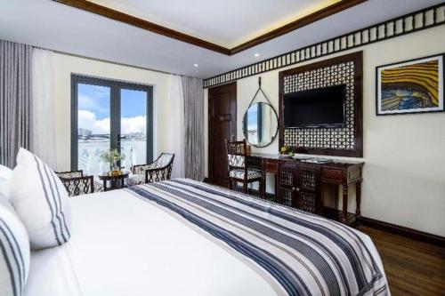 a bedroom with a bed and a desk and a television at Le Pavillon Hoi An Paradise Hotel & Spa in Hoi An