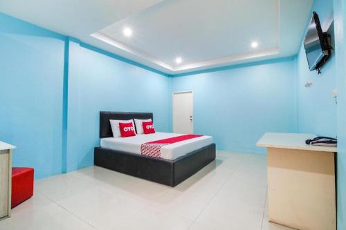 a blue room with a bed with red pillows at OYO 622 Sixsense Hotel in Si Racha