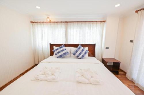 a bedroom with a white bed with blue and white pillows at Chiangkhan Town Hotel in Chiang Khan