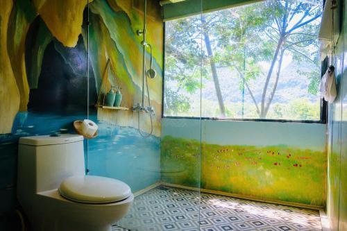 a bathroom with a toilet and a glass shower at Jungle Boss Homestay in Phong Nha
