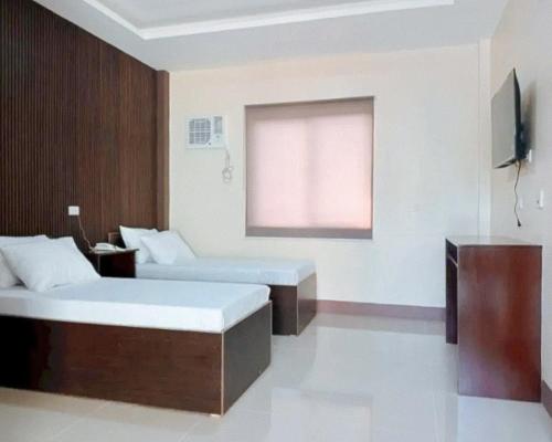 a hotel room with two beds and a window at RedDoorz at Ranchotel Kalibo Aklan in Kalibo
